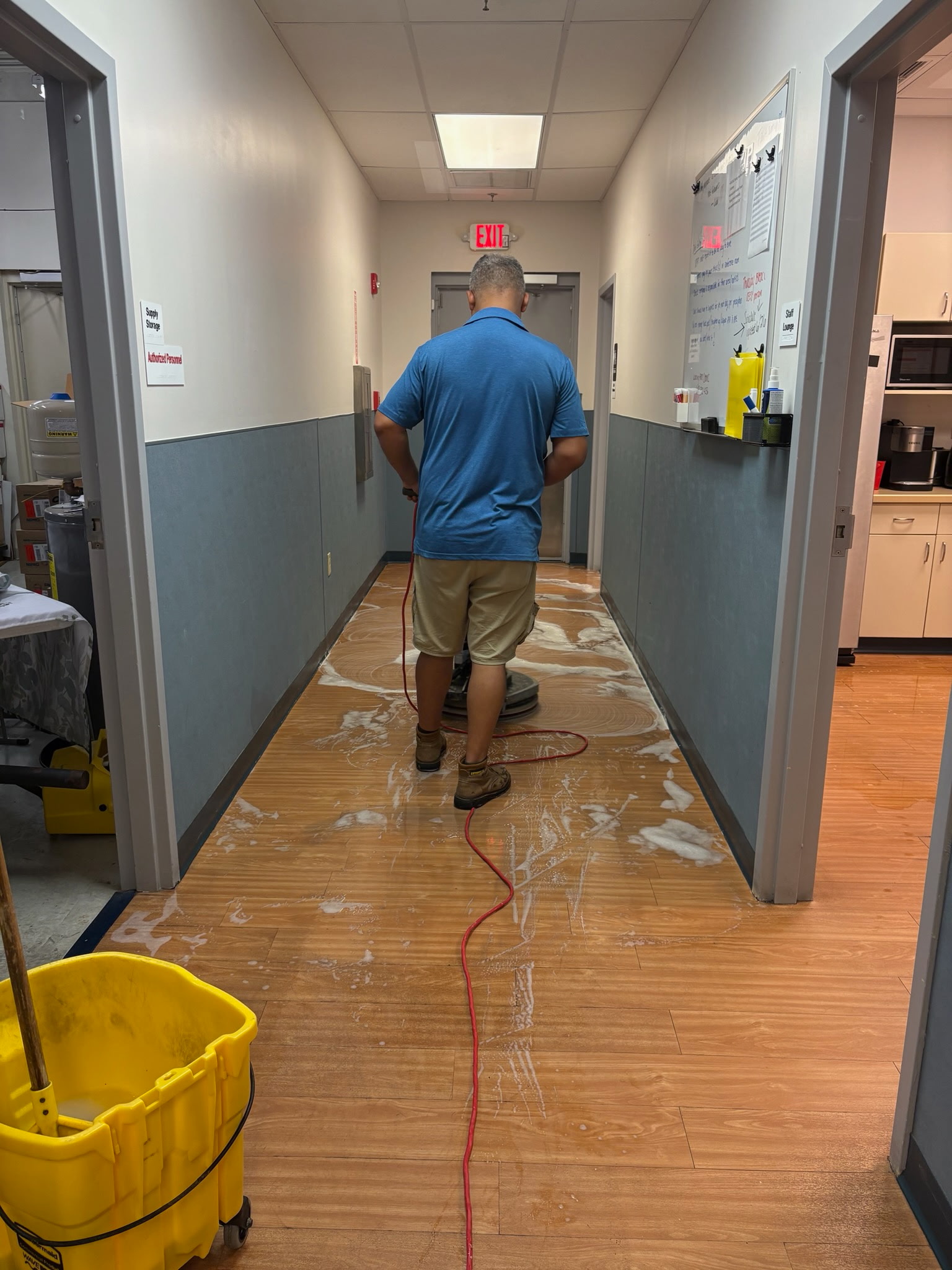 Team member machine-scrubbing a corridor floor