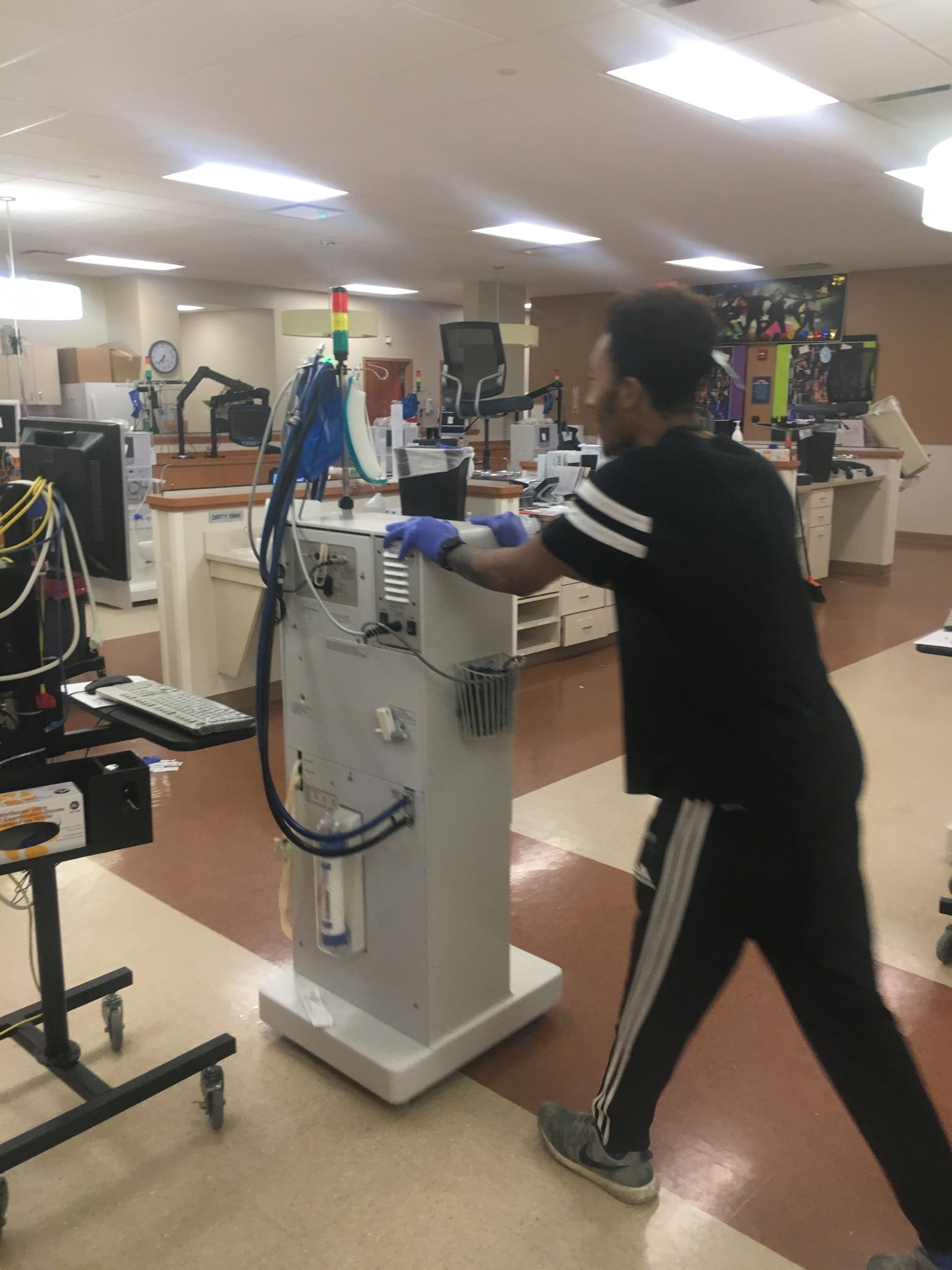 Team member moving a dialysis machine for floor care