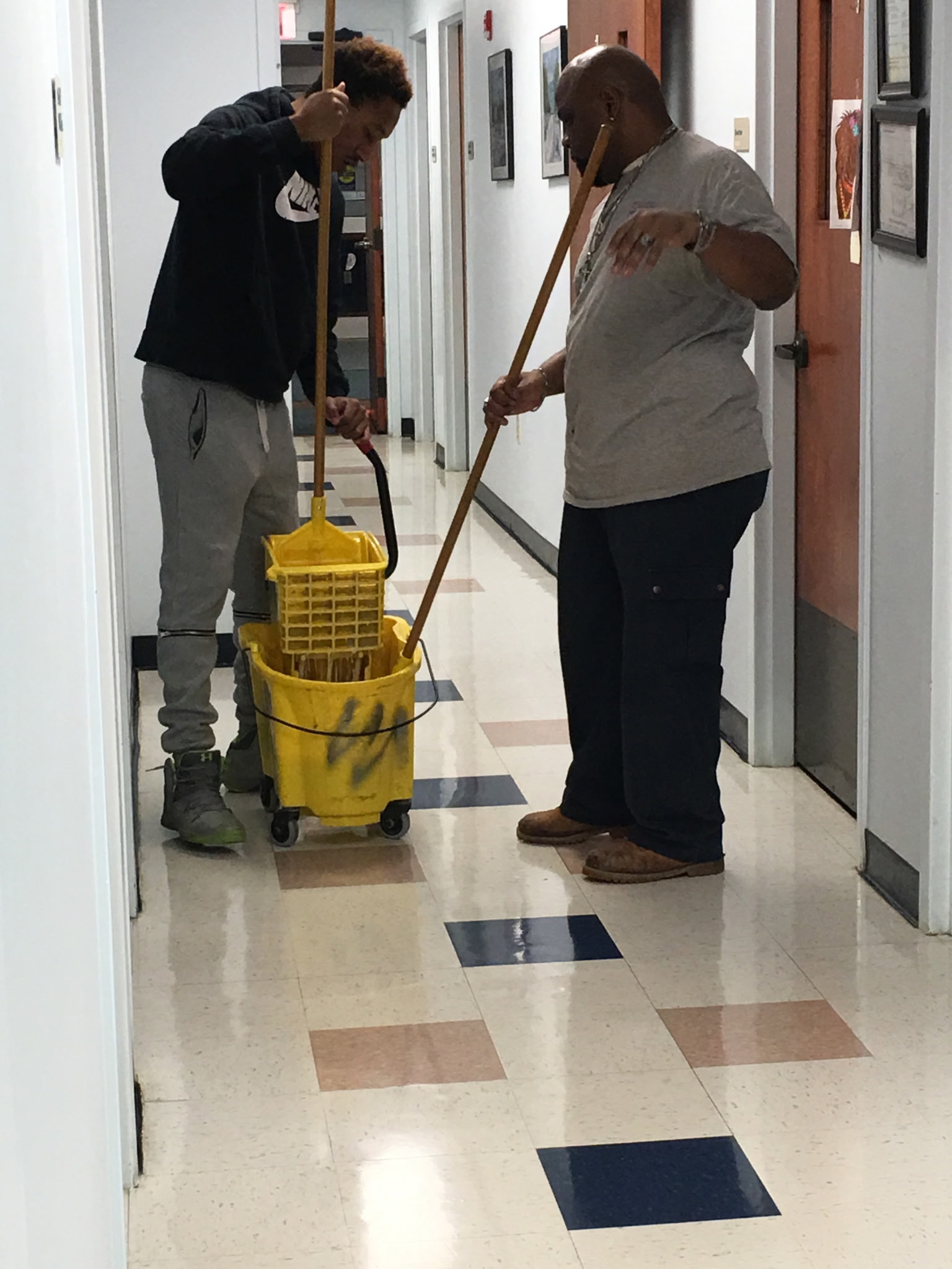 Two team members mopping a clinic corridor